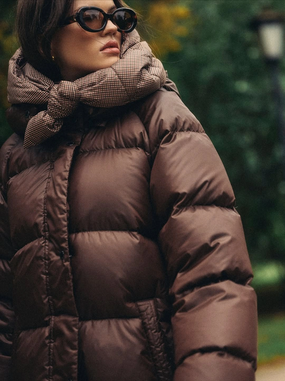 Brown puffer jacket with check scarf and black sunglasses