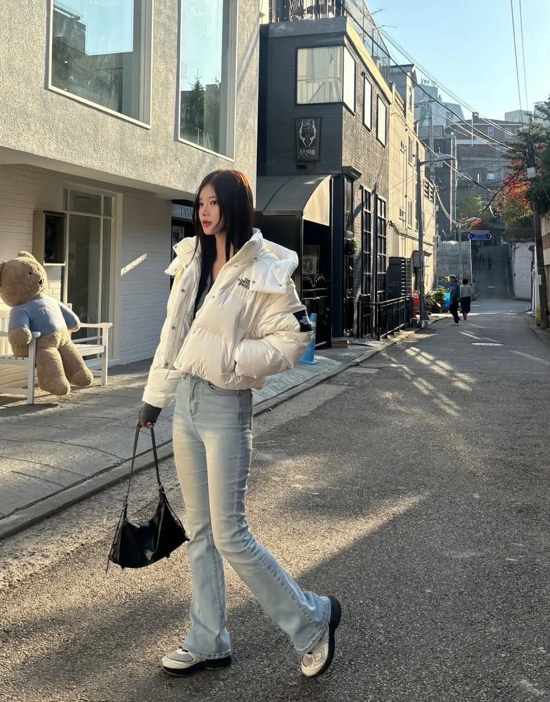 White cropped puffer with light jeans and black handbag