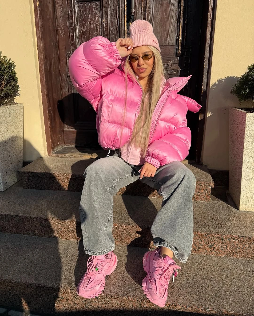 Pink glossy puffer with beanie, gray jeans and sneakers