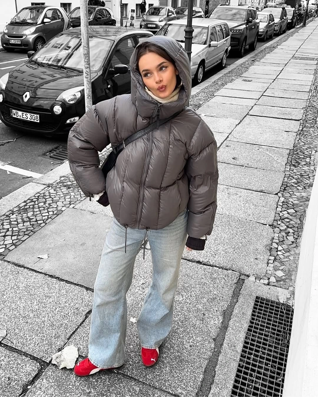 Gray hooded puffer with light jeans and red shoes
