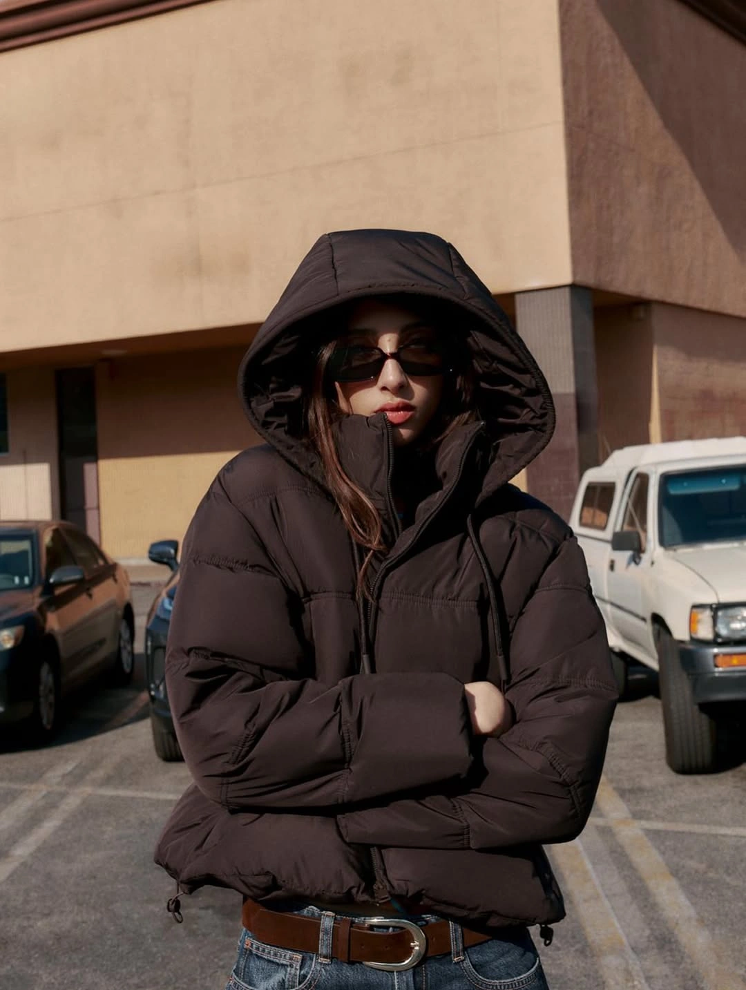 Black hooded puffer with sunglasses, blue jeans and belt