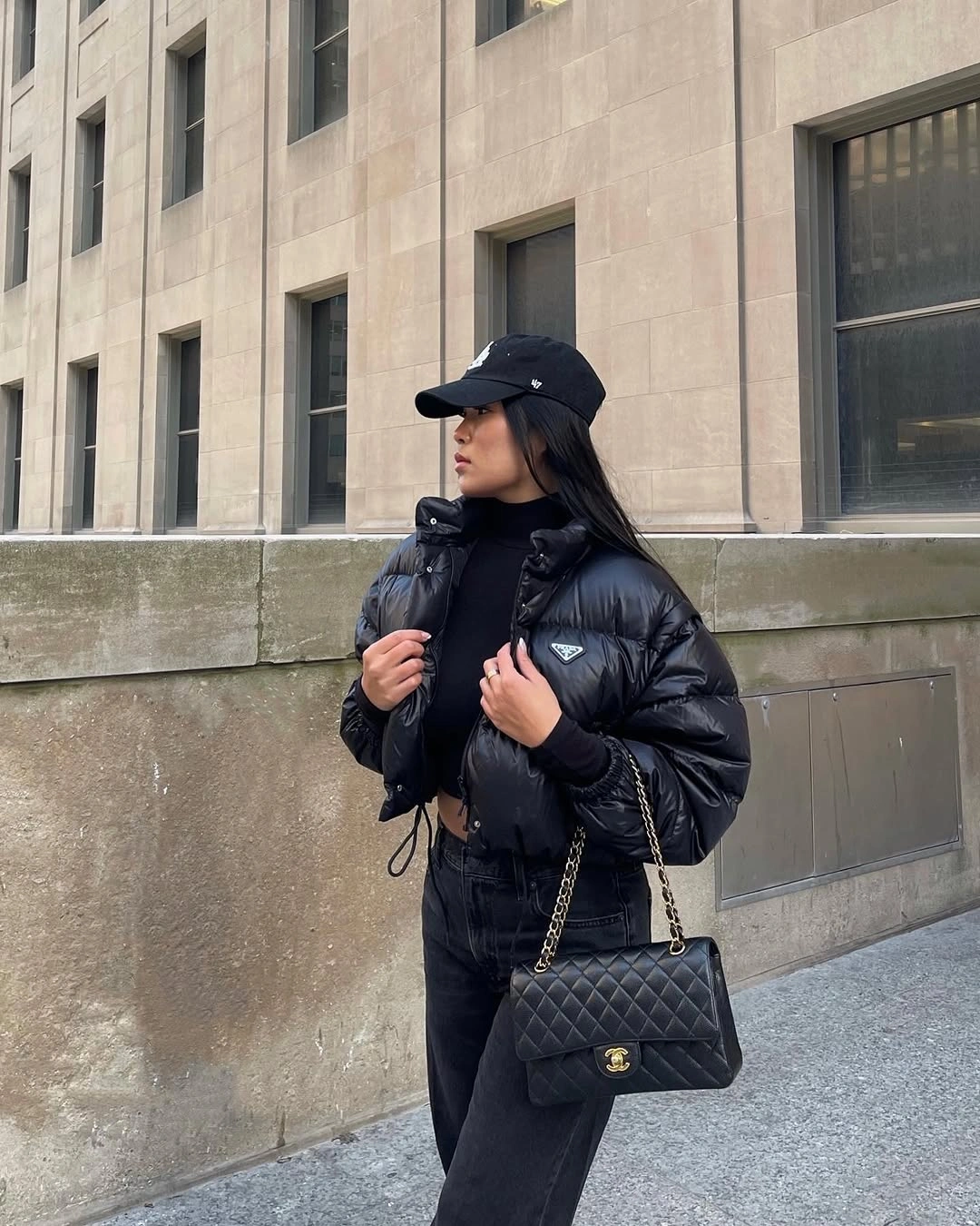 Black cropped puffer with cap, dark jeans and quilted bag