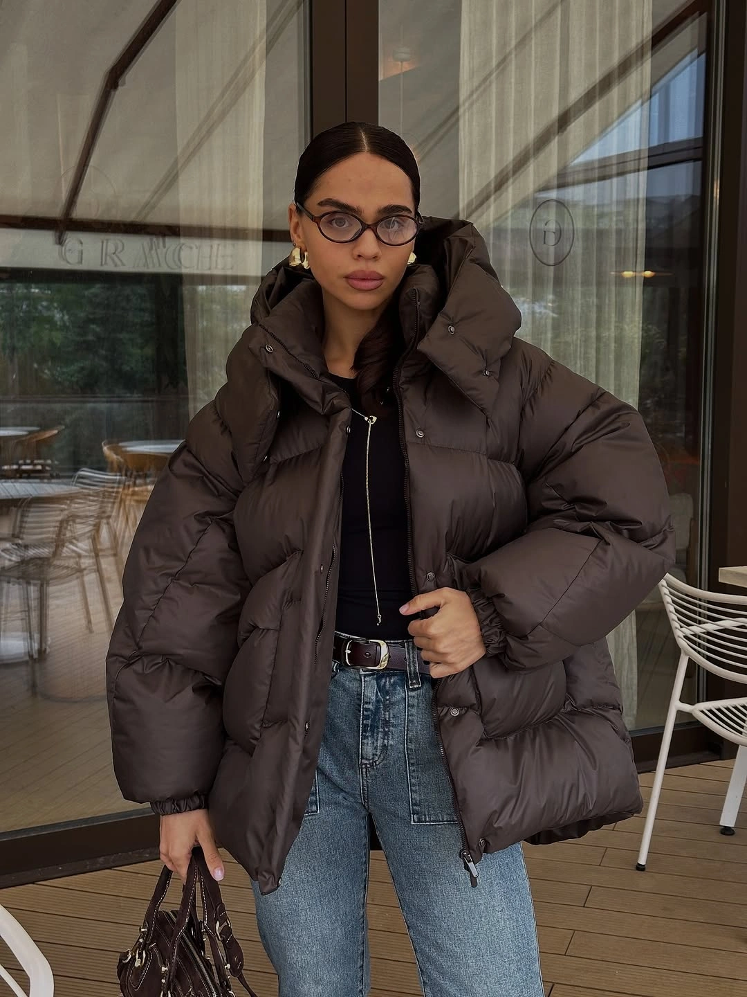 Dark brown oversized puffer with black top and blue jeans
