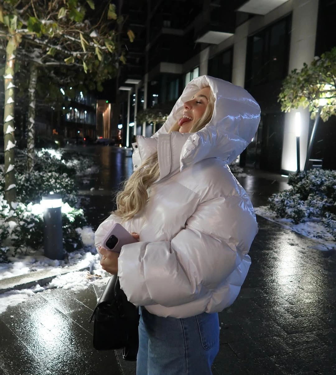 White hooded puffer with jeans, black bag and snow