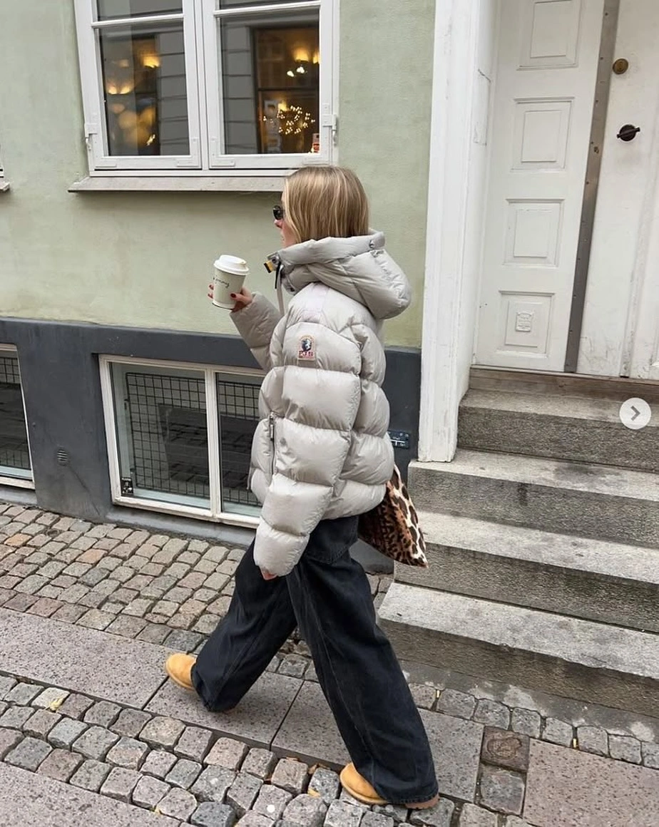 Pale hooded puffer with wide pants, tan shoes and patterned bag