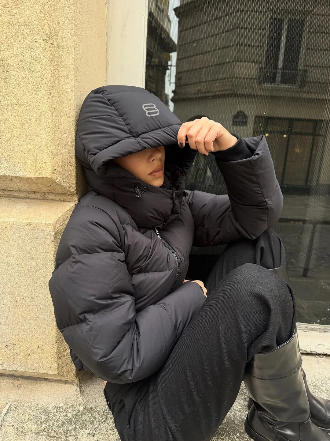 Charcoal hooded puffer with dark wide pants and tall boots