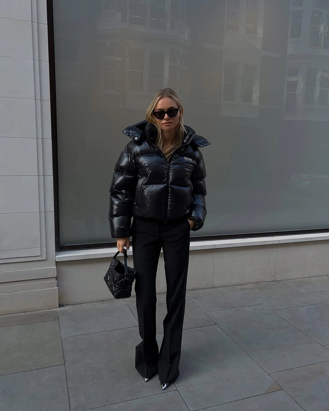 Glossy black cropped puffer with black trousers and pointed shoes