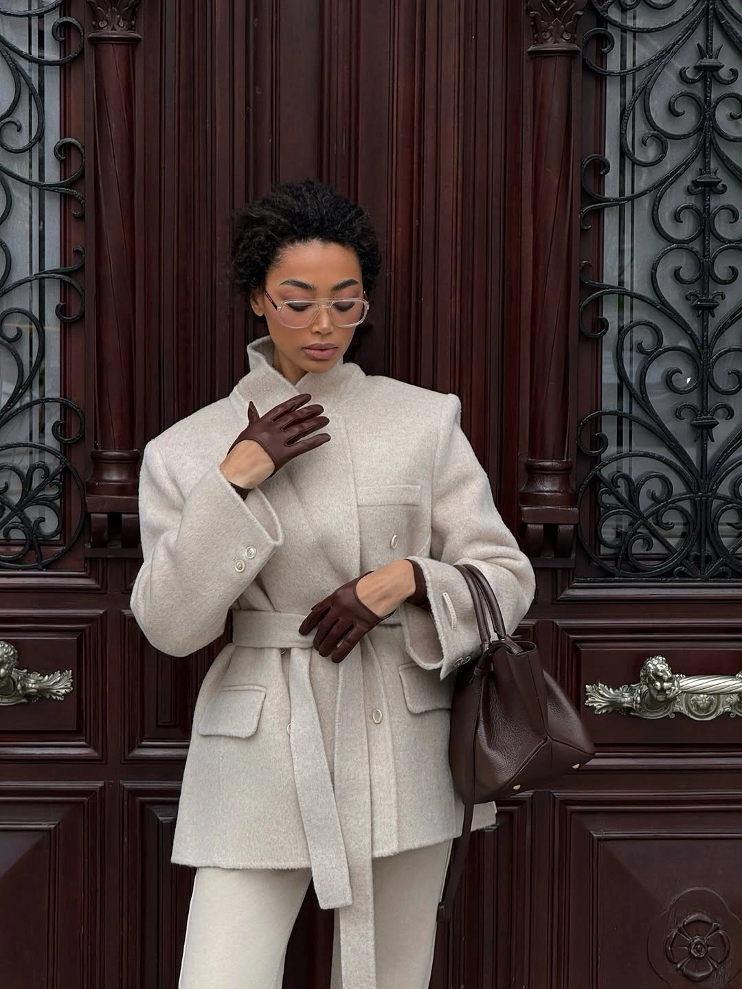 Cream belted jacket with matching pants, brown gloves and handbag