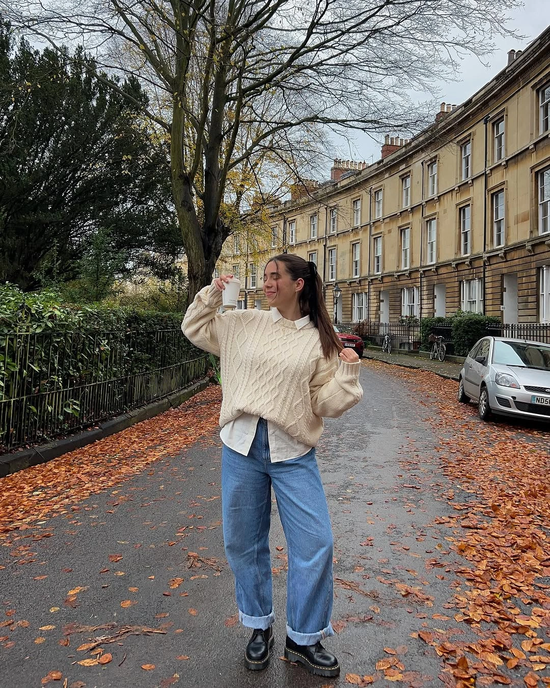 Cream cable knit sweater with cuffed jeans and black loafers