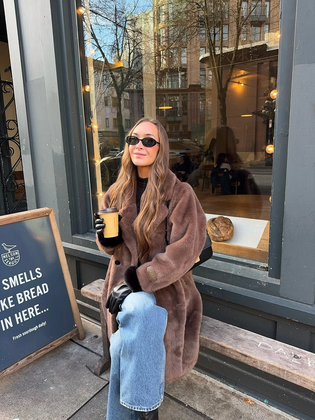 Long brown plush coat with light jeans and black gloves