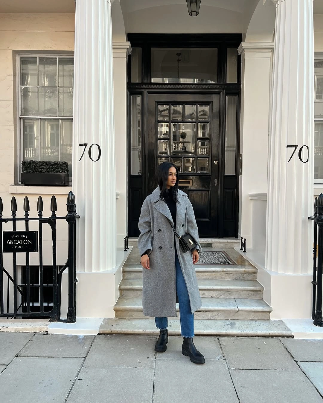 Long gray coat over dark sweater and blue jeans