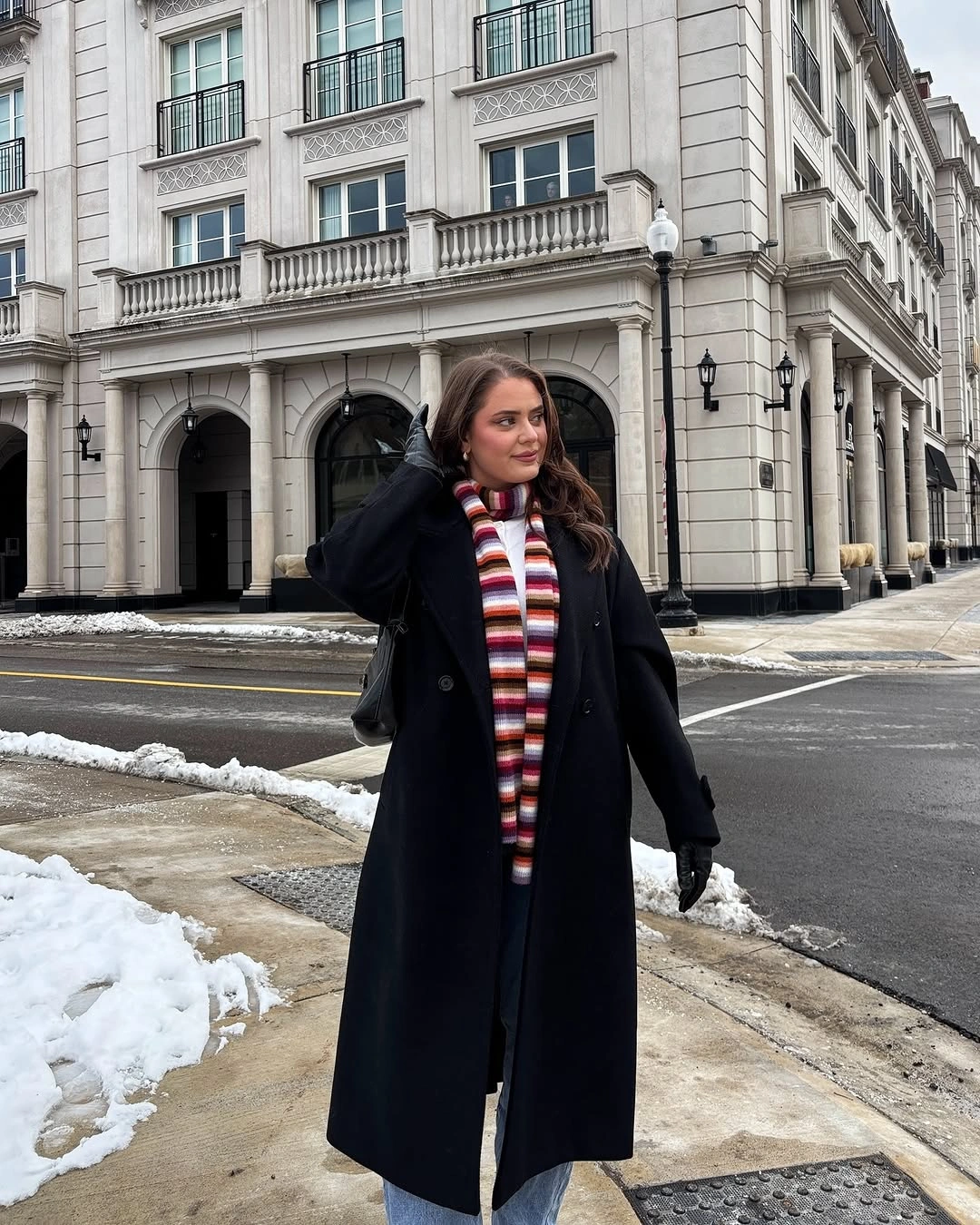 Black coat styled with a bright striped scarf
