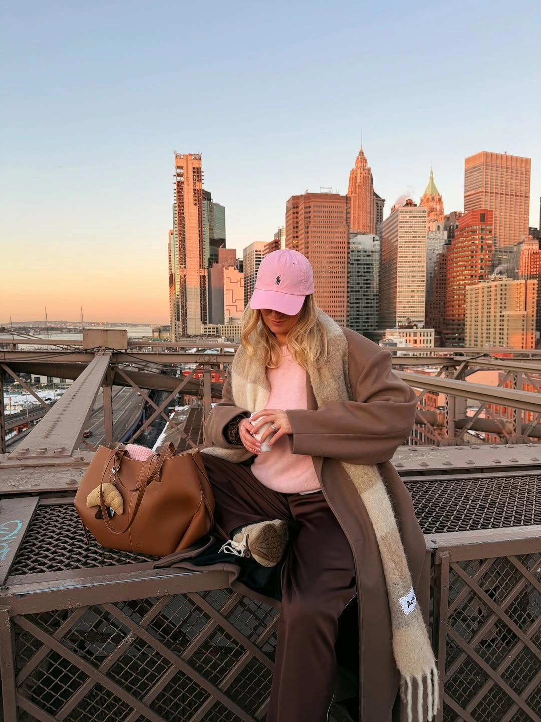 Brown coat with pink cap, scarf and tan handbag