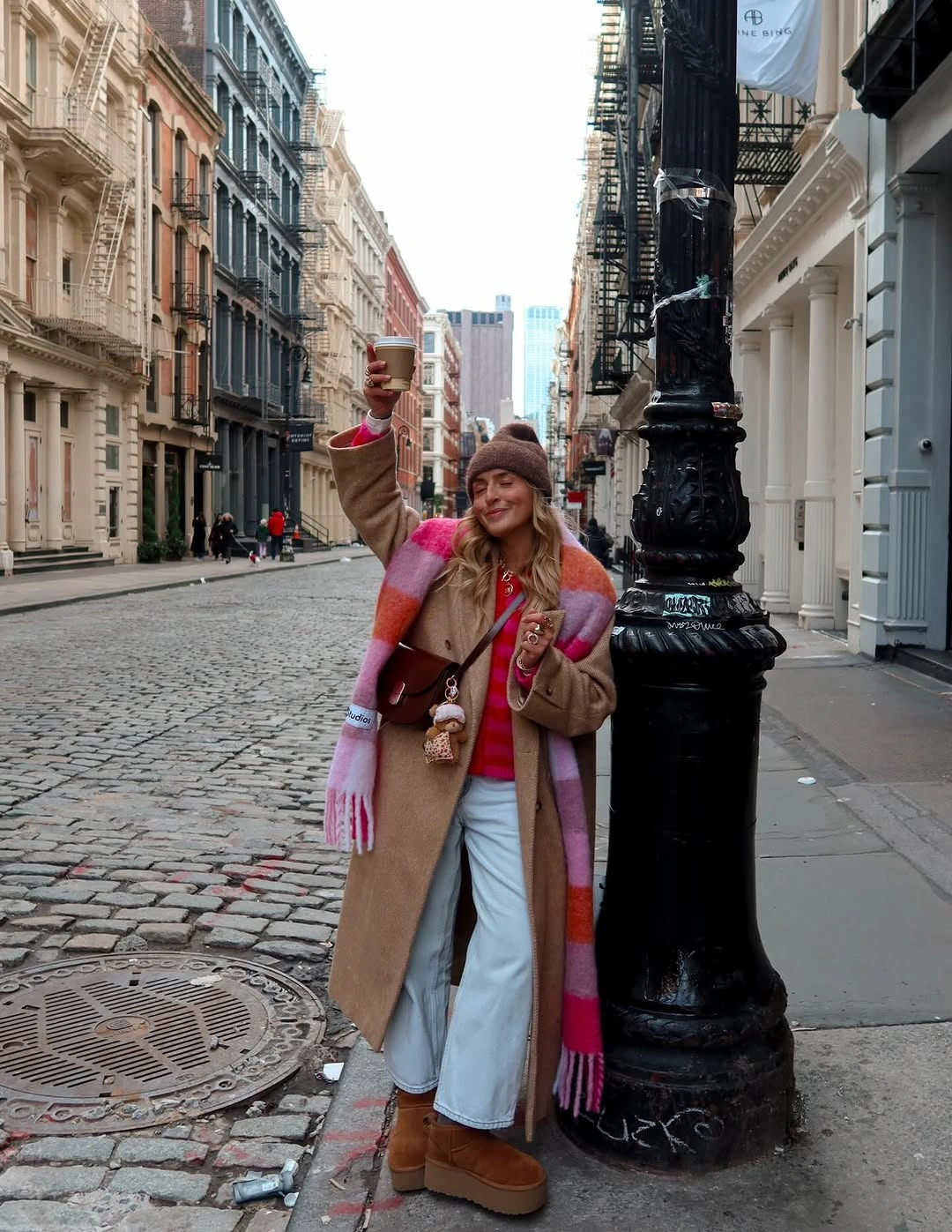 Camel coat with pink striped scarf, white jeans and tan boots