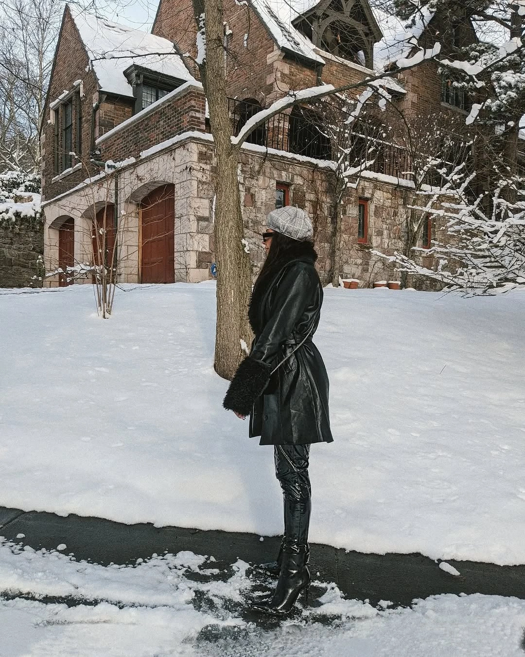 Long dark coat with gray beanie and tall boots in snow