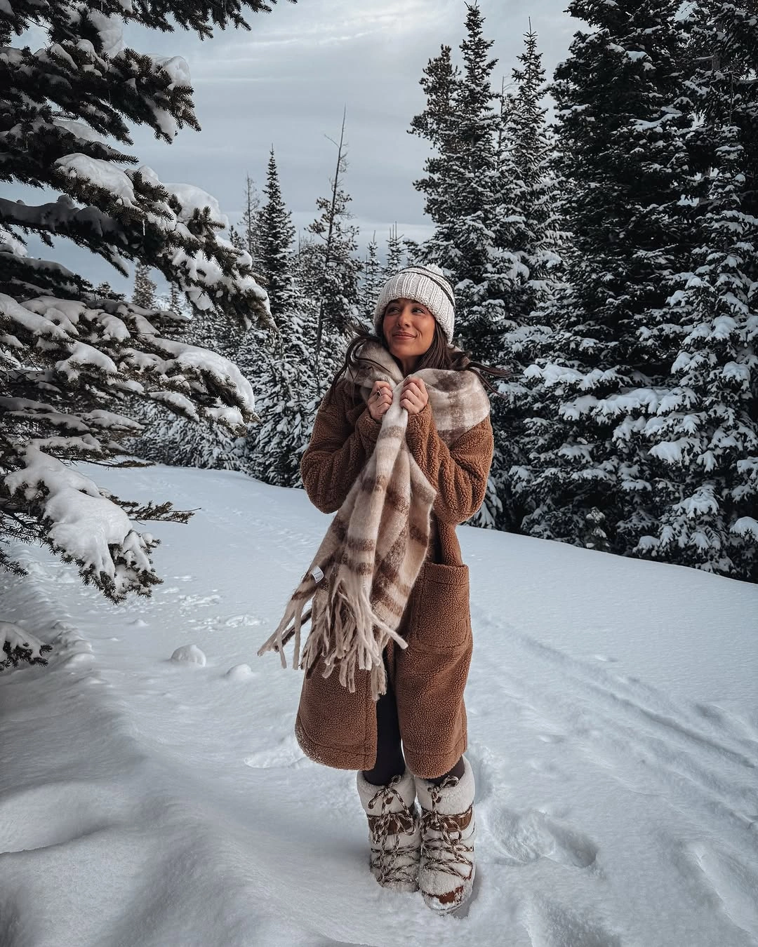 Brown teddy coat, plaid scarf and patterned boots in snow