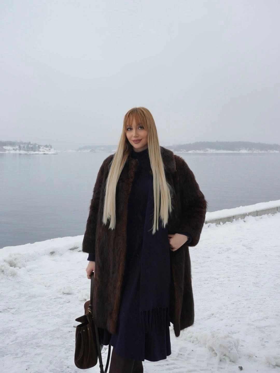 Long dark brown coat, dark scarf and handbag by snow